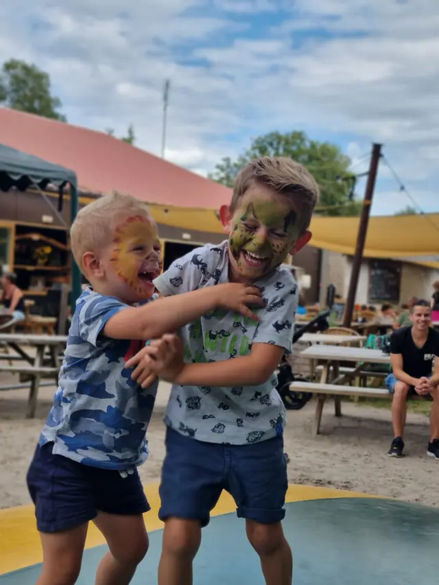 Twee lachende kinderen met geschminkte gezichten samen op het erf