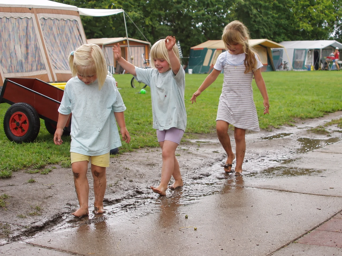 Kinderen lopen op blote voeten door de plassen op het erf