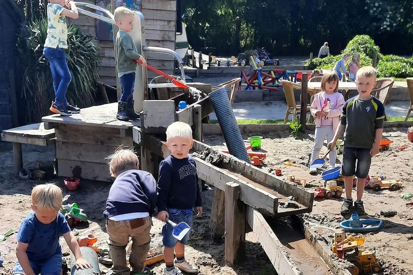 Kinderen spelen met zand en water in de buitenspeeltuin