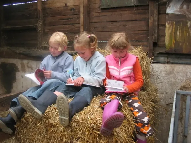 Drie kinderen lezen in het hooi in de grote voorleesboeken