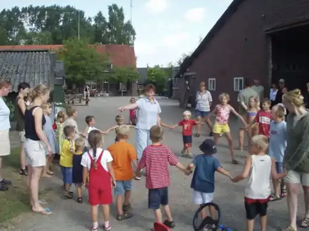 Ons mam Annie met de kinderen in de kring op het erf