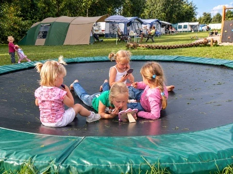 Kinderen op een trampoline bij de kampeerplekken